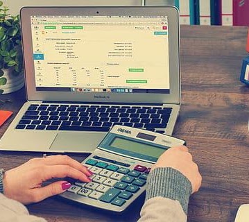 Working through accounts on a laptop with a calculator